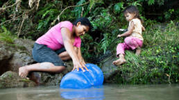 A mother collects water from a spring reachable by canoe